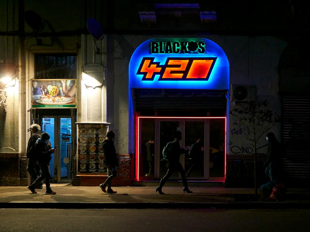 Nighttime street scene in a Chilean city with neon signs and pedestrians