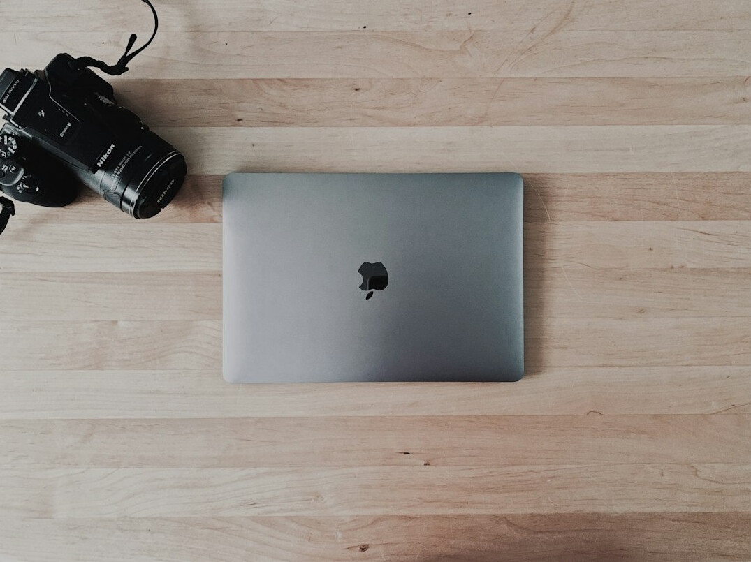 Photographer editing photos on a laptop with contact sheets on the wall